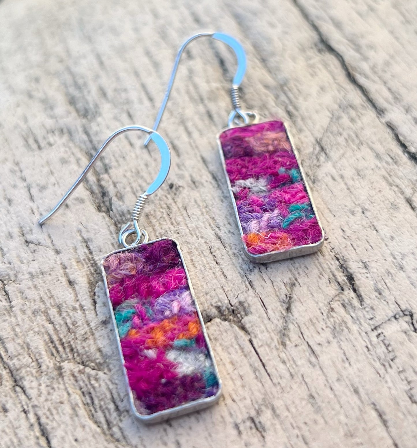 Colorful rectangular earrings on a wooden surface