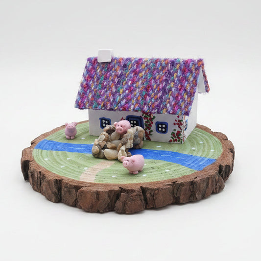 Miniature model of a house with colorful roof and figurines on a wooden base.