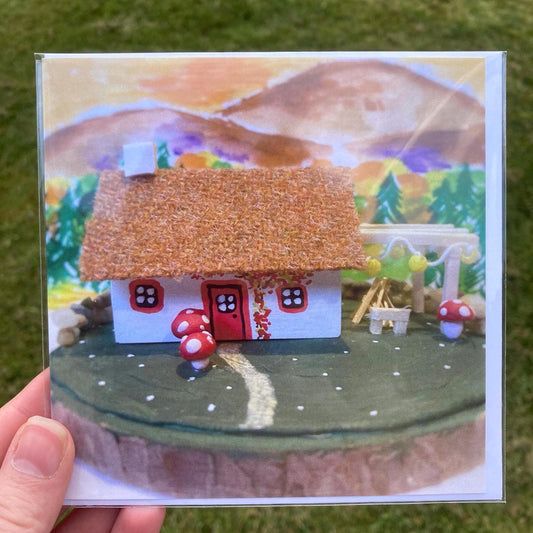 Square greetings card featuring a handmade bothy with mushrooms and a bonfire 