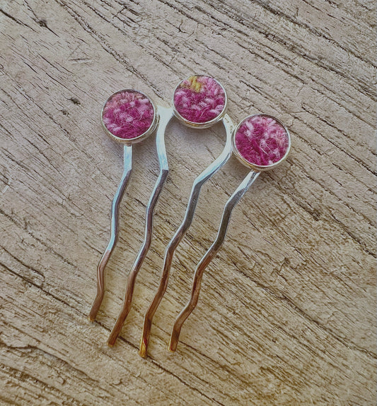 Silver metal hair comb with pink harris tweed accents on a wooden surface
