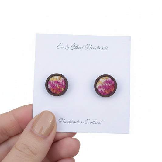 Handmade earrings on a card held by a hand with a neutral background