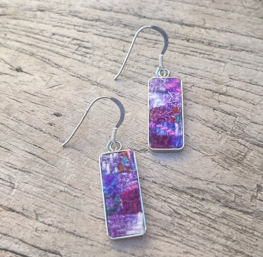 Pair of earrings with colorful rectangular stones on a wooden surface